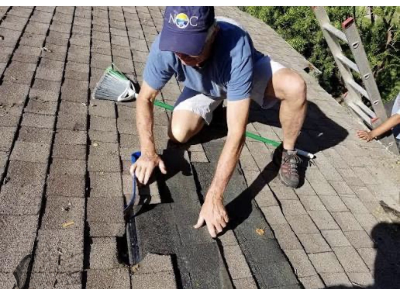 Man repairing roof shingles outdoors.