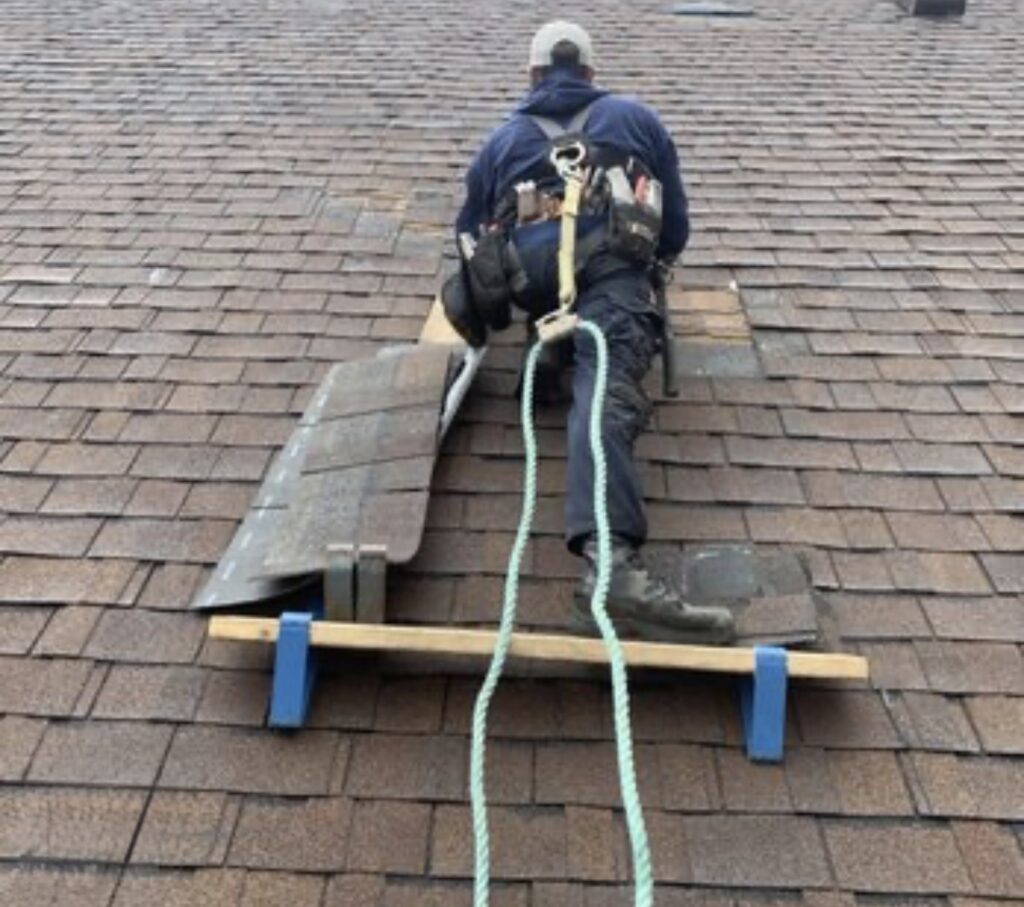 Worker installing shingles on roof